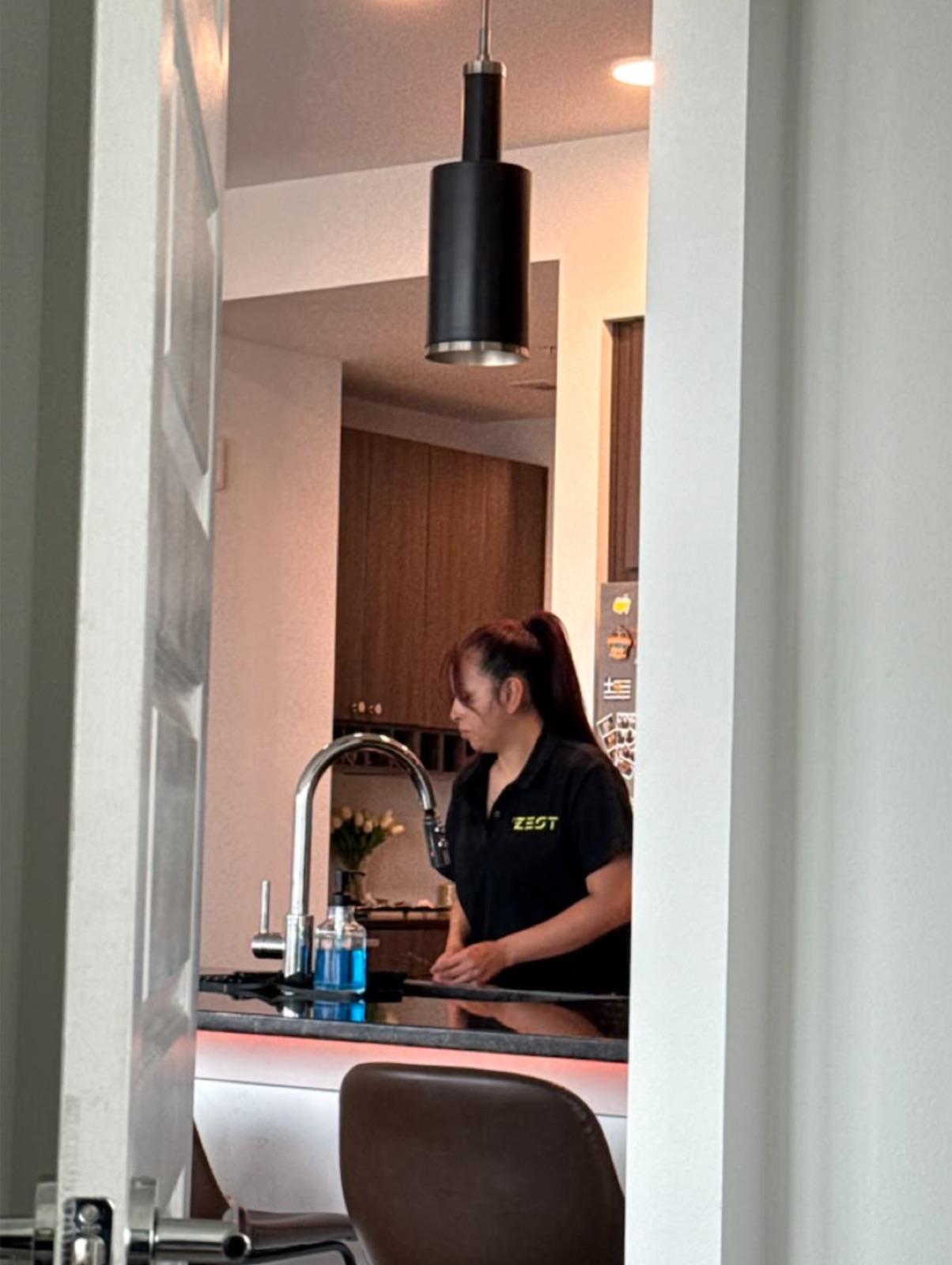 A Zest cleaner in uniform at work in a client's kitchen